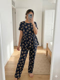 Woman wearing navy blue star and heart print peplum night suit with relaxed fit pants, comfortable homewear set.