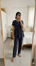 Woman wearing black floral print peplum night suit with relaxed fit pants, soft comfortable homewear set.