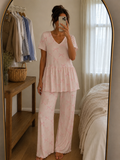 Woman wearing a blush pink ribbon print ribbed knitted cotton peplum night suit with V-neck top and matching straight-fit lounge pants by Irah Vastra.